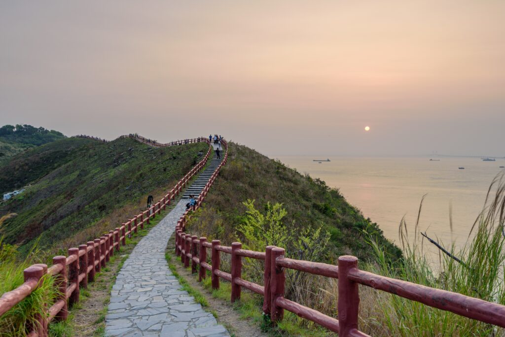 people going through a narrow route with a red fence during the sunset